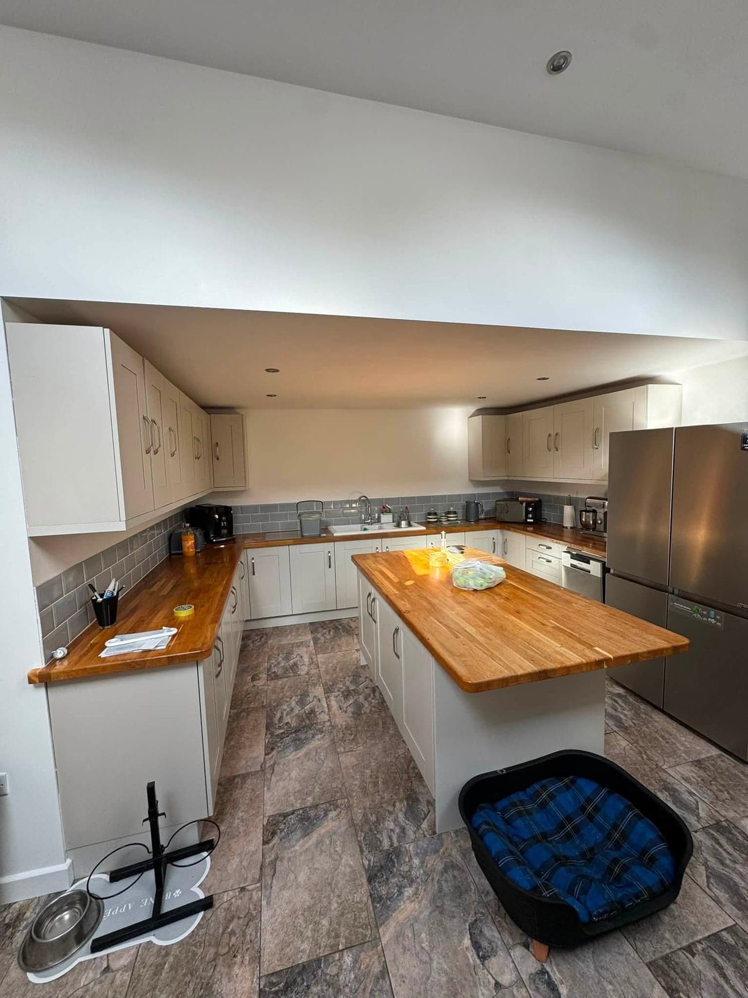 Kitchen with pale grey painted units, oak worktops and a central island under a freshly painted white ceiling