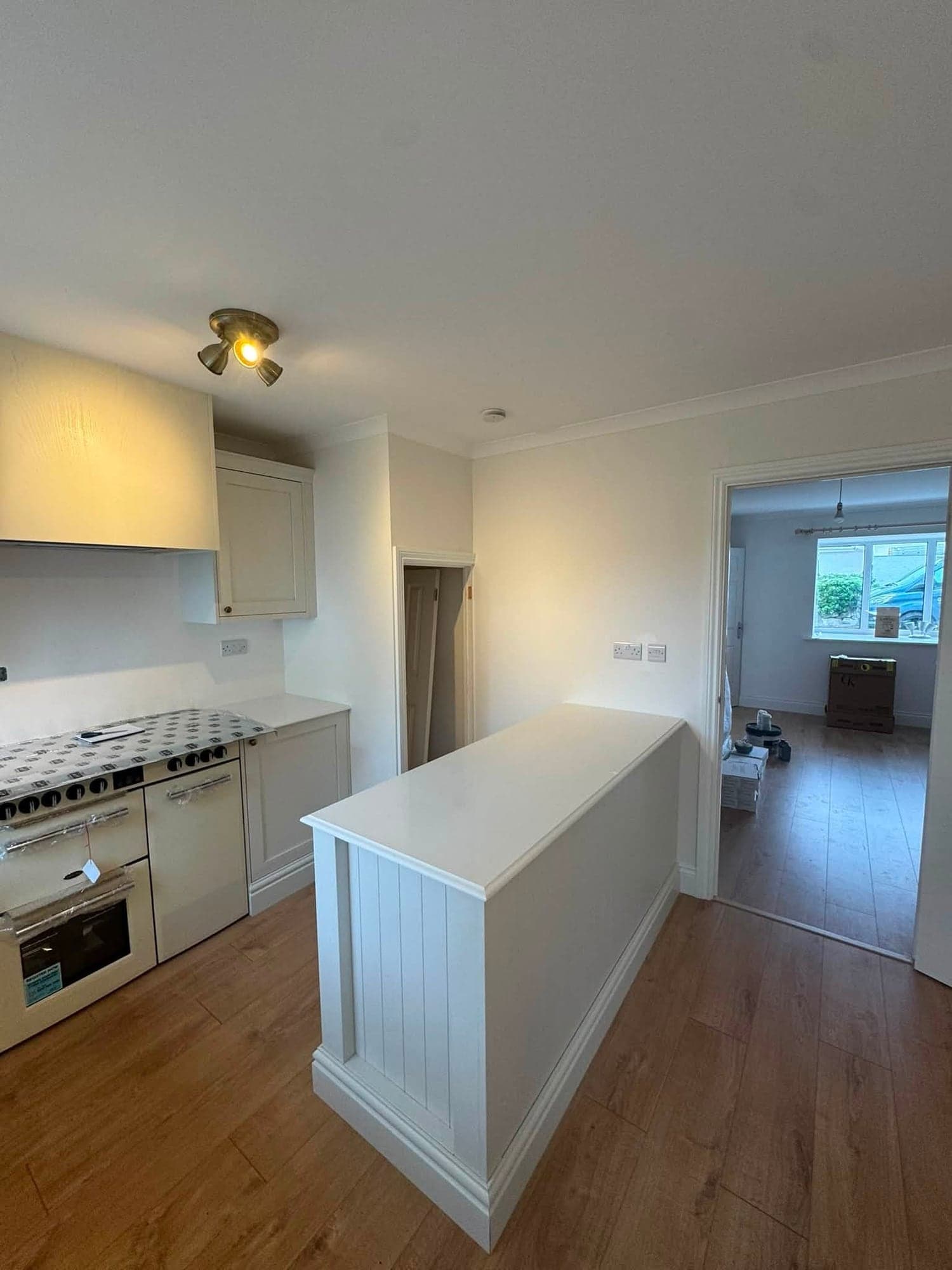 Painted kitchen peninsula with tongue-and-groove panelling, a cream range cooker and a doorway through to a bright living room